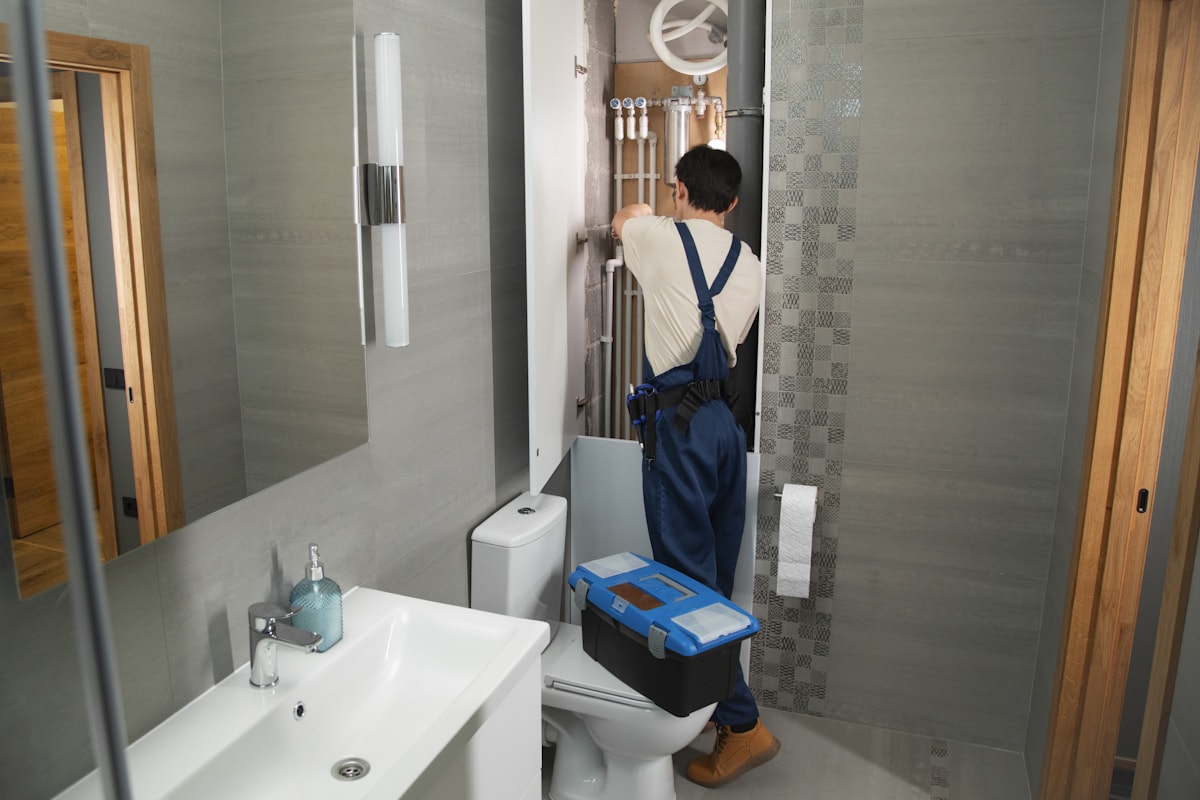 Auckland plumber working on bathroom pipework