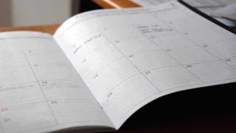 Open desk calendar planner showing a monthly grid of dated squares